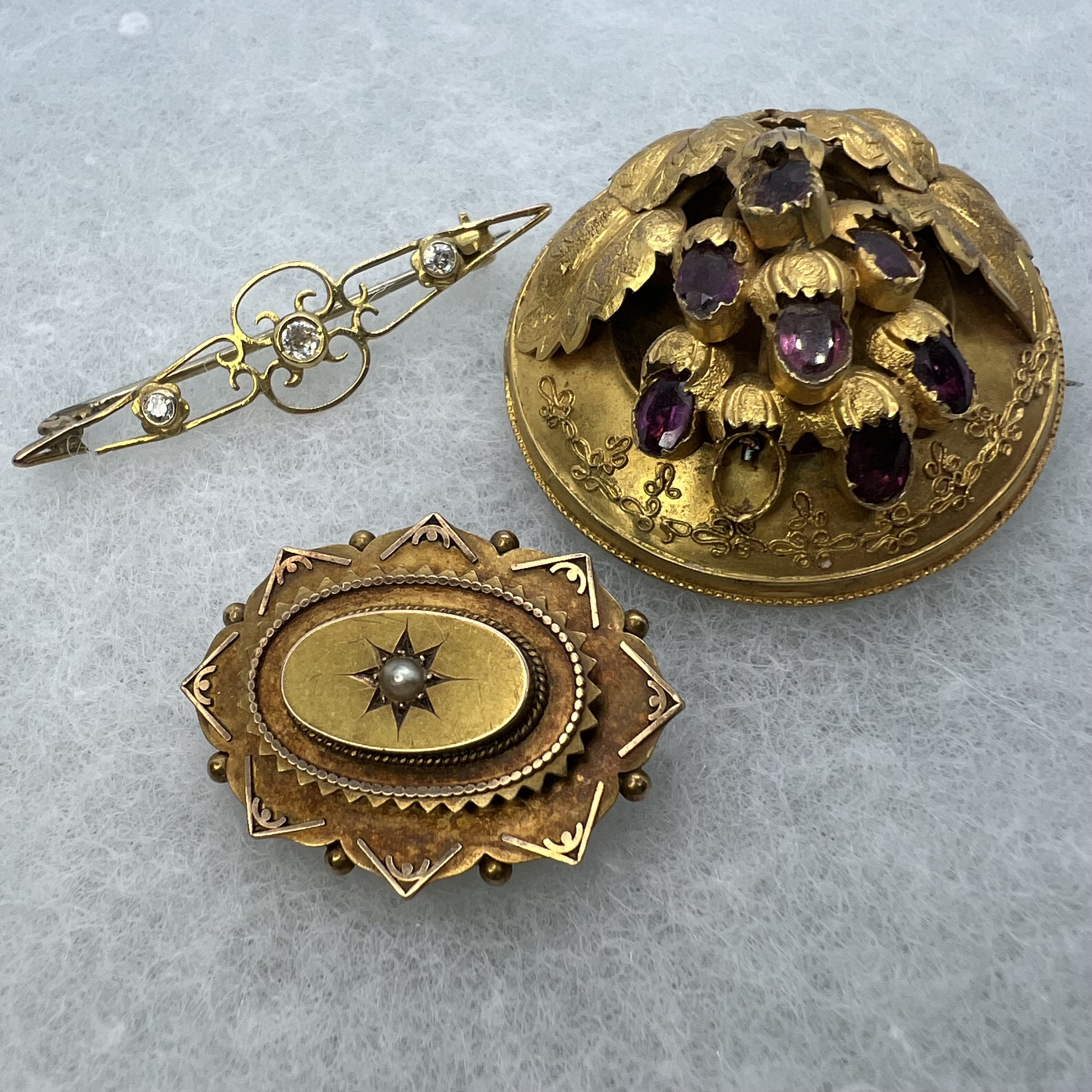 A collection of three antique brooches in precious yellow metal. Featuring a Victorian Etruscan