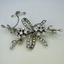 A 1960s 18ct white gold and diamond spray brooch in a bow tied design. Set with 27 round brilliant