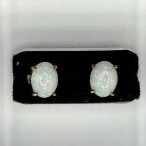 A pair of white opal cabochon ear studs in precious yellow metal. Featuring opal cabochons measuring