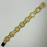 A Chinese character bracelet in precious yellow metal. Featuring eight circular panels, with seven