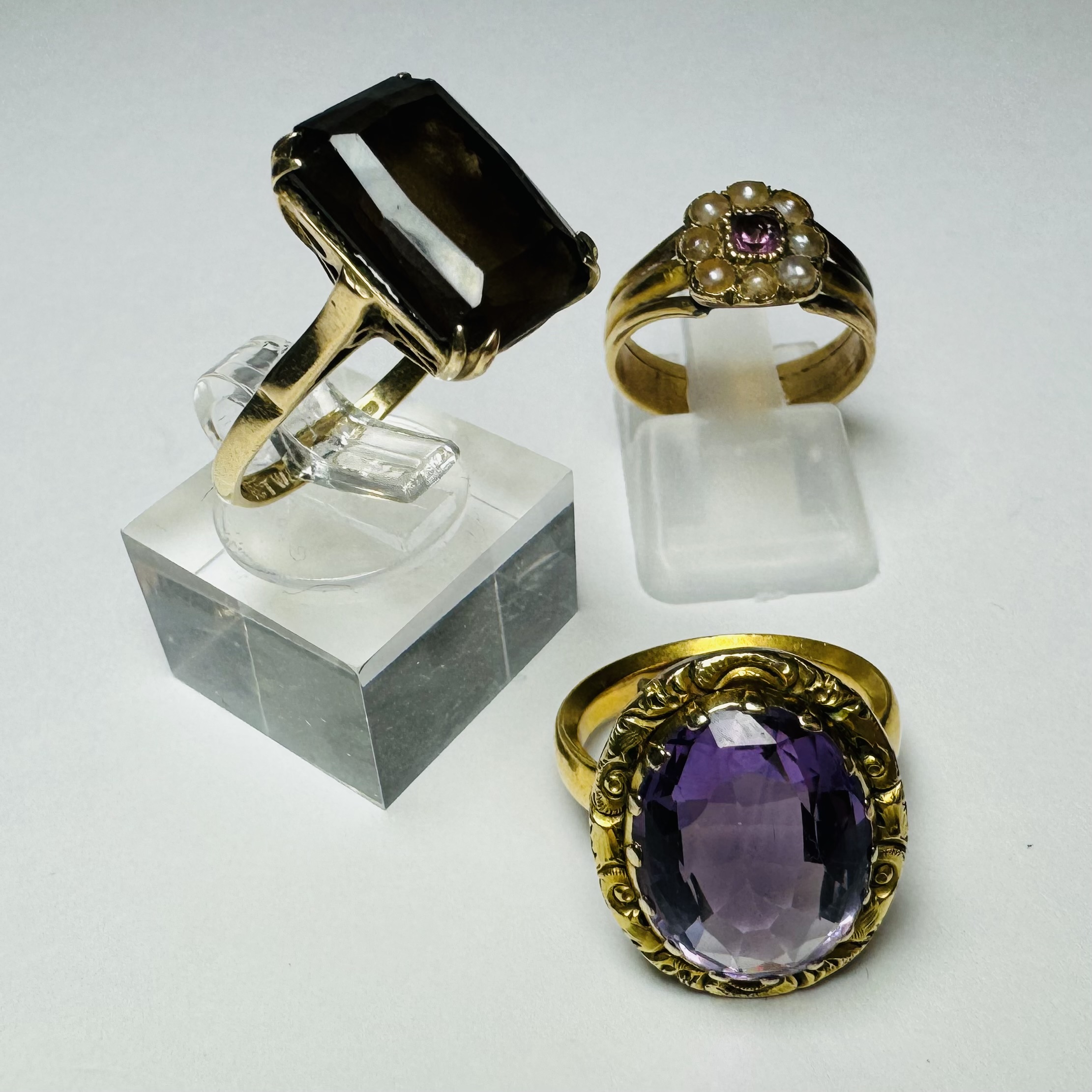 A collection of three dress rings. Comprising a 9ct gold smoky quartz cocktail ring, size O,