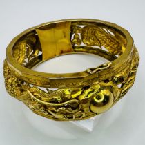 Chinese Dragon and pearl motif open work hinged bangle. Stamped "22K" and marked with Chinese