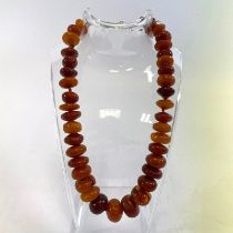 An Amber bead necklace.  40cm long and the largest bead 18mm by 12mm.  Approximate weight 60 grams.