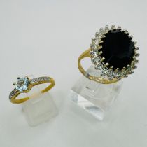 A pair of gold plated costume jewellery rings, one set with a large oval black stone, surrounded