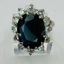 A large sapphire and diamond cluster ring in 18ct white gold. The dark blue, oval mixed cut