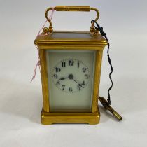 A brass carriage clock with a key. Approximately 15cm tall with handle up. Working, glass and dial