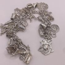 A silver charm bracelet. Approximately 107 grams. With 31 charms that include: Noah's Ark, London