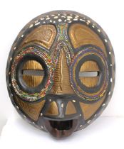 A 20th century Bembe tribal mask, Zambia, large wooden mask decorated with black and gold and beaded