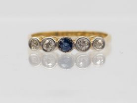 A diamond and sapphire set 18ct gold five stone ring, comprising a central round mixed cut sapphire,