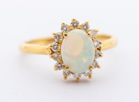 An opal and diamond oval 18ct gold cluster ring, set with an oval opal, approx 7.9mm, within a