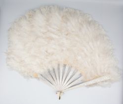 An early 20th century curly Ostrich feather fan with painted wooden stays.