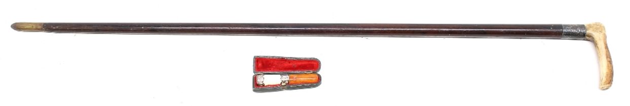 An early 20th Century silver collared walking stick with cased cigarette holder.