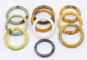 A collection of ten jade/ hardstone bangles in varying shapes and sizes and colours including