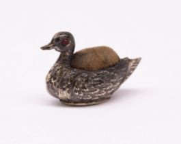 An Edwardian silver novelty pin cushion in the shape of a duck, having ruby glass eyes, hallmarked