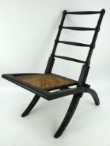 An Aesthetic Movement ebonised folding chair with rattan seat in the style of E W Godwin,