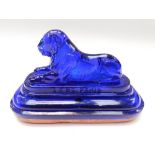 A novelty French cobalt blue glass lion-shaped paperweight with terracotta oval base. The lion is