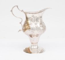 A George III silver ogee shaped cream jug, chased with swags of foliage and roundels, the front