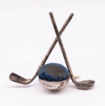 An Edwardian silver novelty pin cushion in the form of golf clubs flanking a central spherical