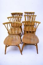 A mid 20th Century Ercol drop leaf kitchen table with six matching dining chairs.