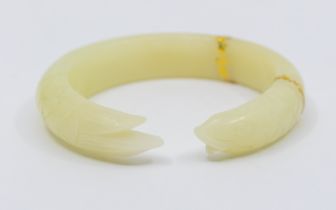 A carved nephrite jade torque bangle, carved in the form of a fish, with overlaid gilt decoration,