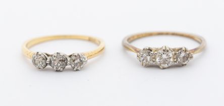 Two diamond and 18ct gold three stone rings, the largest central diamond approx 0.30ct, (both with