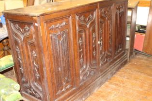 An early 20th century "Gothick" oak cabinet with linenfold and scroll carving moulded edge above a
