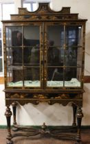 A 1920's black lacquer glazed display cabinet in 18th century style with shaped cornice above a pair