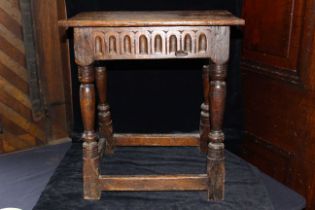 A 17th century style oak joint stool with carved frieze on baluster turned legs joined by plain