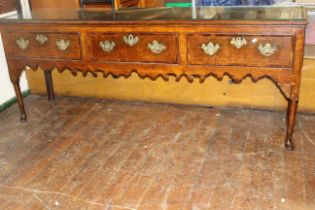 A George III oak dresser with moulded edge above three crossbanded frieze drawers, shaped apron,