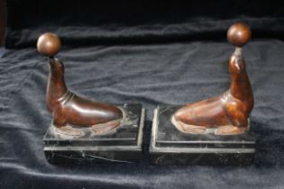 A pair of Art Deco style bronze bookends modelled as seals on stepped marble bases, 15cm high