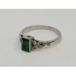 An 18ct. white gold, diamond and emerald ring, having baguette cut emerald in rub over setting to