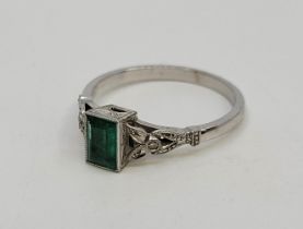 An 18ct. white gold, diamond and emerald ring, having baguette cut emerald in rub over setting to
