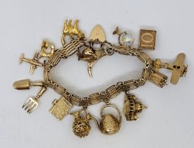 A gold charm bracelet, the 9ct. gold gate bracelet with heart padlock clasp suspending 12 x 9ct.