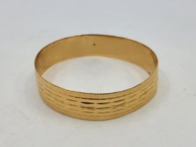 A precious yellow metal bangle, with engraved decoration to exterior (yellow metal assessed as