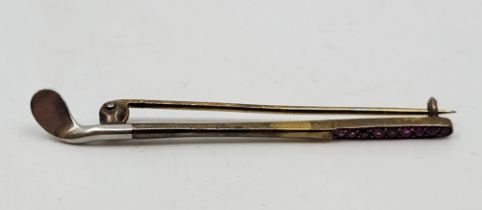 Golf Interest: A bi-colour metal and ruby bar brooch, fashioned as a golf club, with handle pave set