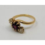 A precious yellow metal, diamond and garnet cross-over ring, set mixed round cut garnet flanked by