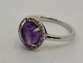 A 9ct. white gold, amethyst cabochon and diamond halo ring, set round cabochon amethyst to centre