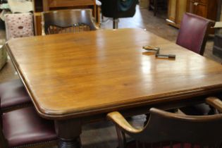 A Victorian mahogany wind out dining table on pot castors with two leaves and a handle, together