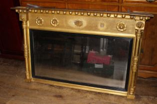 A Regency gilt gesso overmantel mirror, the rectangular plate in reeded ebonized fillet flanked by