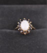 A 9ct Yellow Gold Opal and Sapphire Ring. The Oval Cabochon Opal measures approx. 8.36mm x 6.16mm. x