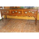 A George III oak dresser with moulded edge above three crossbanded frieze drawers, shaped apron,