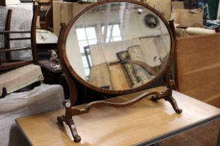 A Georgian style mahogany swing toilet mirror, the oval plate on scroll support and feet joined by