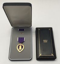 A United States cased Purple Heart medal, complete with full sized ribbon bar, and a miniature