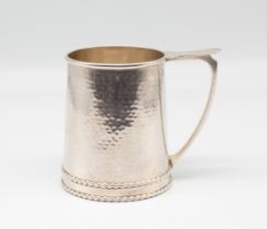 A. E. Jones - an Arts & Crafts style silver childs can/mug, having planished body with relief ribbed