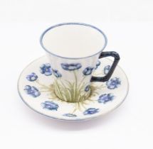A Macintyre Moorcroft cup and saucer, with poppy design on white background, made for Twiss Bros