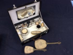 A 1930s black vanity case with contents to include perfume/powder bottles, mirror and a mid 20th