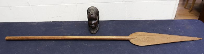 A hardwood carved African head along with a wall hanging African spear.