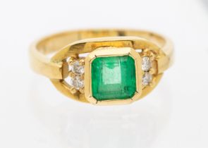 An emerald and diamond 18ct gold ring, comprising a central Columbian emerald cut emerald,