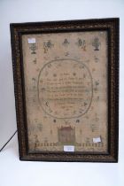 An 1807 George III sampler by Charlotte Clements in a frame.