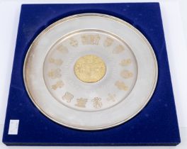 A commemorative Elizabeth II silver circular dish with central raised gilt roundel with coat of